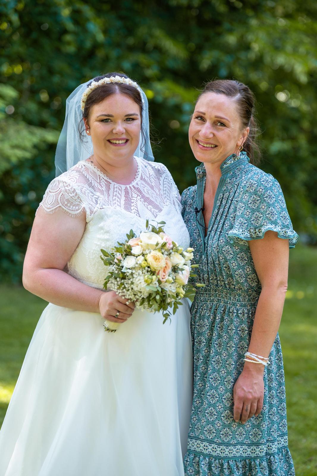 Antje Scholz mit der Braut im Brautkleid mit Schleier und Brautstrauß nach der freien Trauung im Grünen